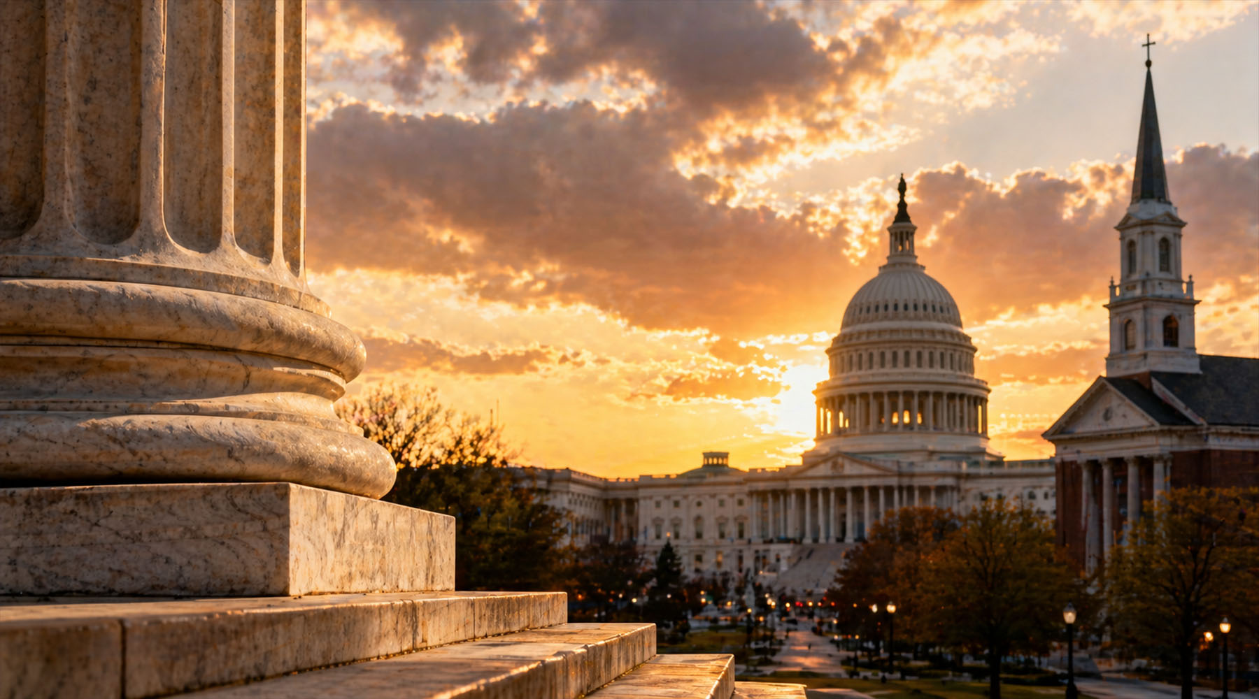 Sunset view of the U.S. Capitol building alongside a church with a tall steeple, seen from stone steps and columns in the foreground, with warm light and dramatic clouds over the city.